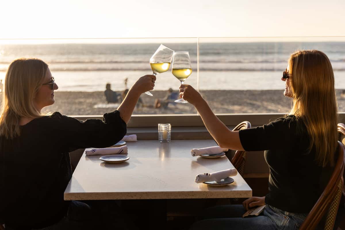 Two women cheering wine glasses