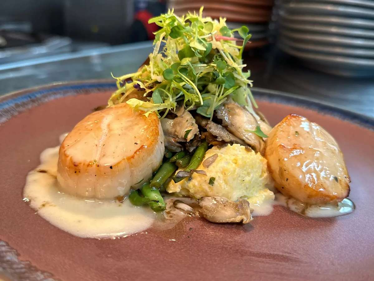 Seared Hokkaido scallops served with mascarpone mashed potato, market vegetables, tamari-pickled beech mushrooms, lotus root chips, and miso-ginger ponzu.