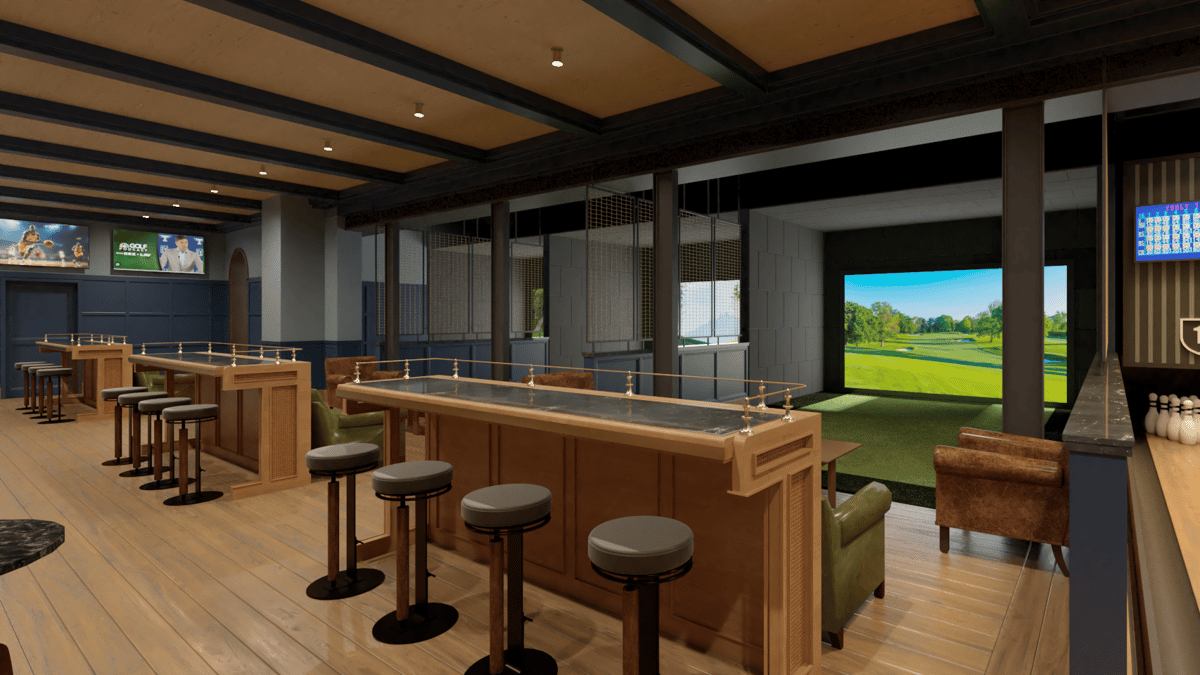 Upscale sports bar interior with communal high-top tables, leather lounge seating, and an indoor golf simulator screen in a modern entertainment-driven restaurant.