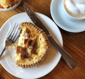 Ham and egg quiche on a plate with a fork and knife