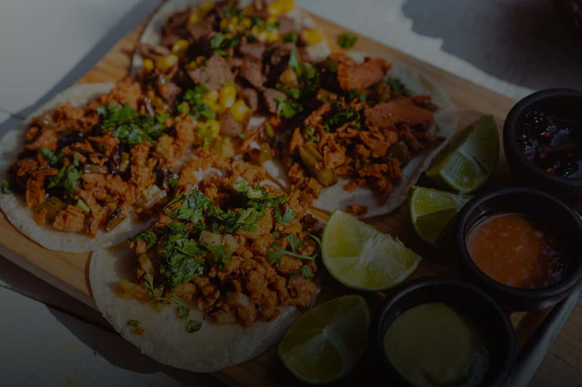 Close-up of savory tacos with fresh lime wedges and colorful sauces.