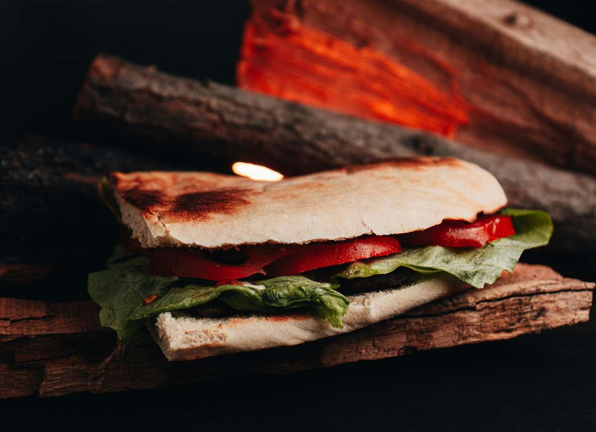 A toasted sandwich with lettuce and tomato on a rustic wooden background, perfect for food enthusiasts.