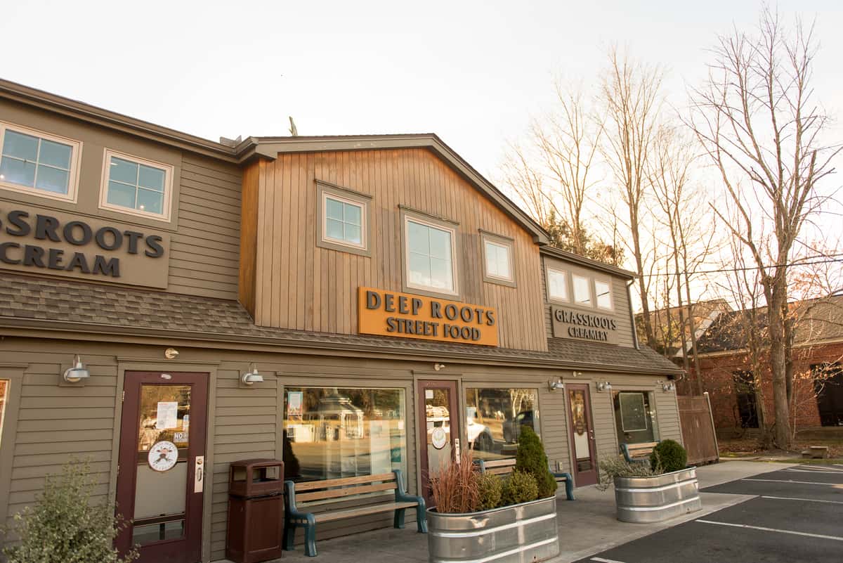 Exterior of Grassroots Creamery and Deep Roots Street Food building at sunset with warm lighting and rustic facade, inviting local eatery
