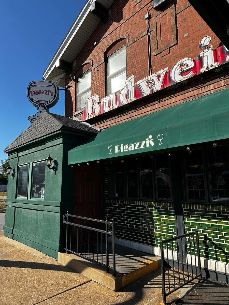 Close-up of Rigazzi's restaurant entrance with green awning, Budweiser sign, and signature frosted goblet logo.