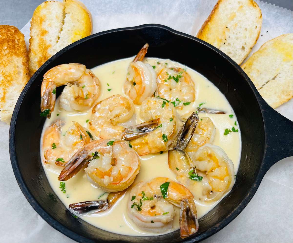 shrimp in creamy sauce with garnish and bread on the side