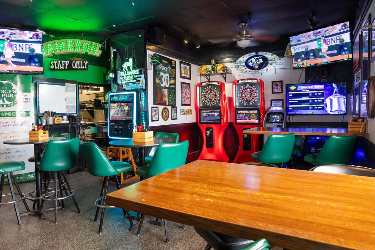 Sports lounge interior featuring dart machines, large-screen TVs, and comfortable seating for guests.