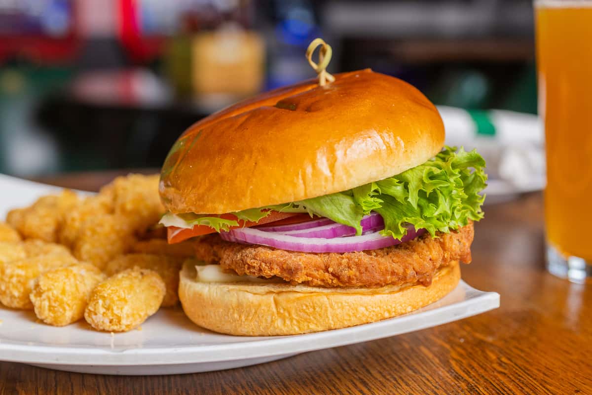 Breaded pork tenderloin sandwich served with crispy tater tots and classic pub-style sides.