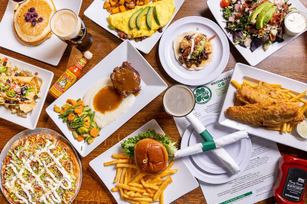 Overhead spread of burgers, sandwiches, salads, seafood, and cocktails showcasing the restaurant menu.