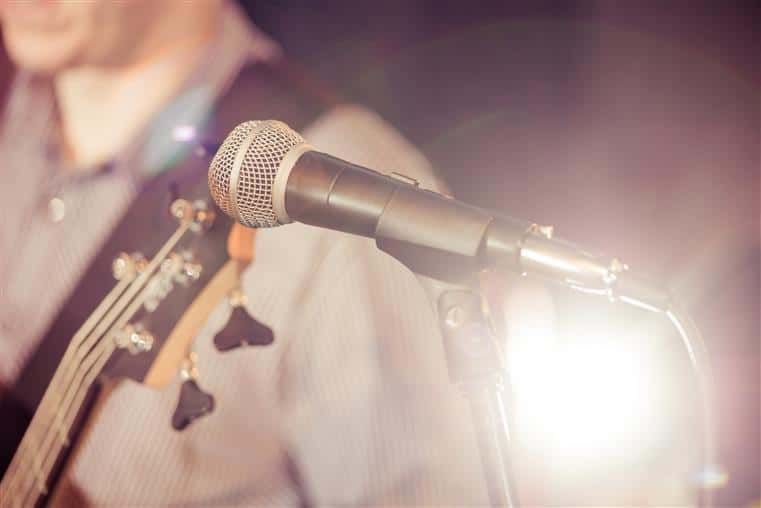 closeup of a microphone with a guitar player in the background