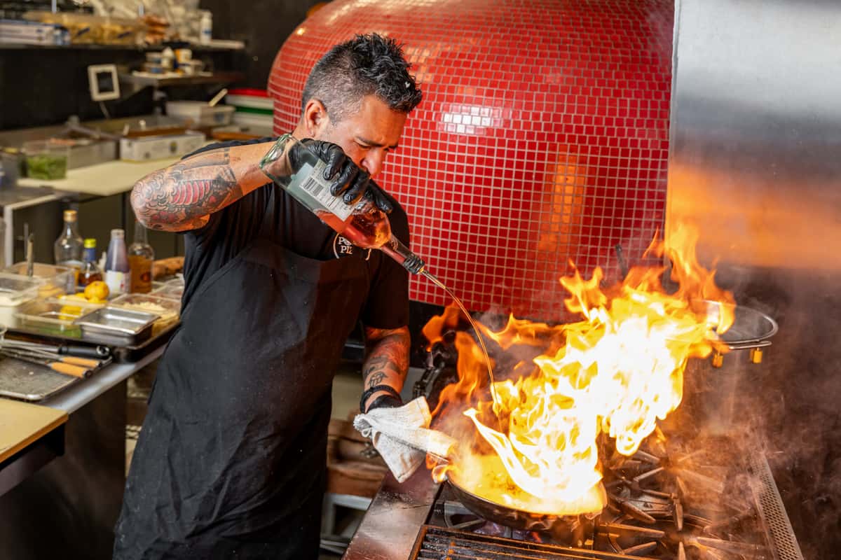 staff preparing pizza with large flame