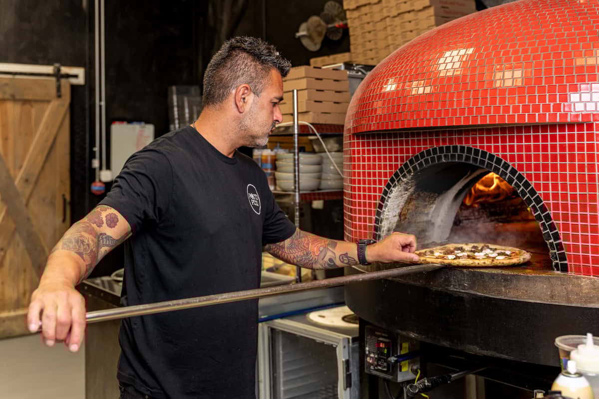 staff putting pizza in the oven