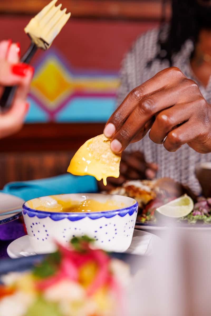 Hand dipping a chip in queso