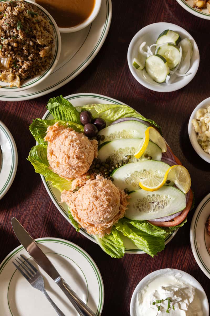 Salmon and whitefish salad platter with cucumbers and capers at Famous 4th Street Delicatessen — kosher-style Yom Kippur catering favorite.