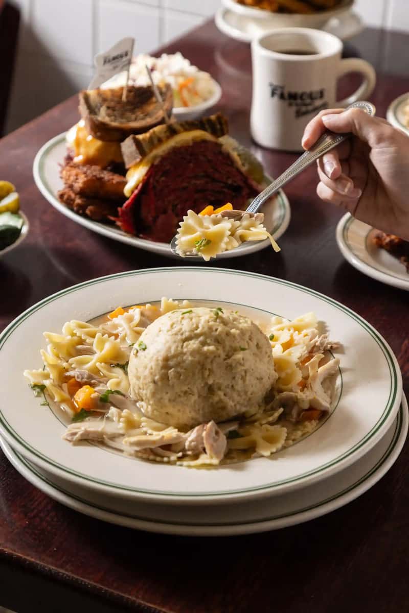 Warm bowl of matzo ball soup with noodles and chicken at Famous Deli — classic Jewish-style comfort food from one of America's best kosher-style delis.