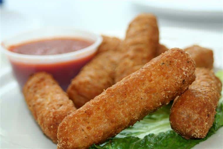 fried mozzarella sticks over a bed of greens with a side of marinara sauce.