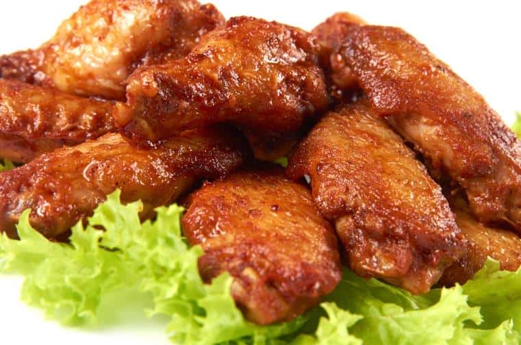chicken wings tossed in hot sauce over a bed of greens
