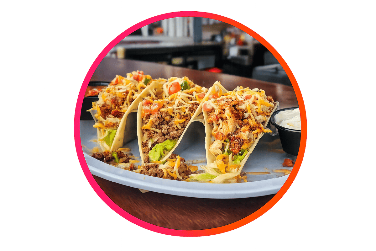 Three soft-shell tacos filled with seasoned beef, grilled chicken, shredded cheese, lettuce, and pico de gallo, served with sour cream and salsa at The Boxer Kitchen & Bar.