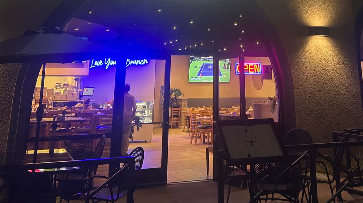 Exterior nighttime view of a restaurant with illuminated interior seating.