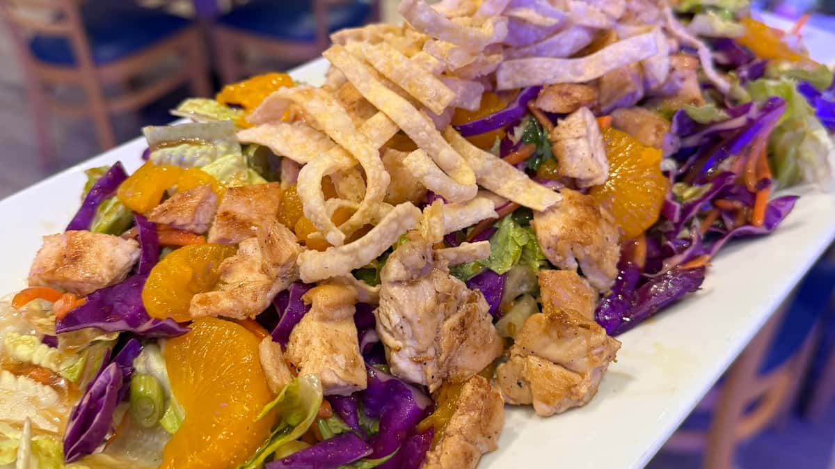Grilled chicken salad with shredded cabbage, crispy tortilla strips, and mandarin oranges.