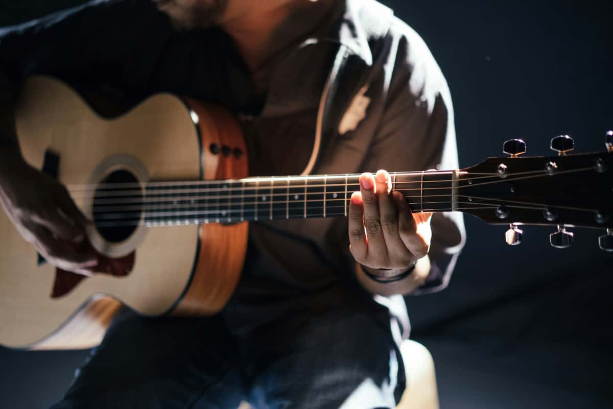acoustic guitar close-up with hands strumming strings in warm ambient lighting