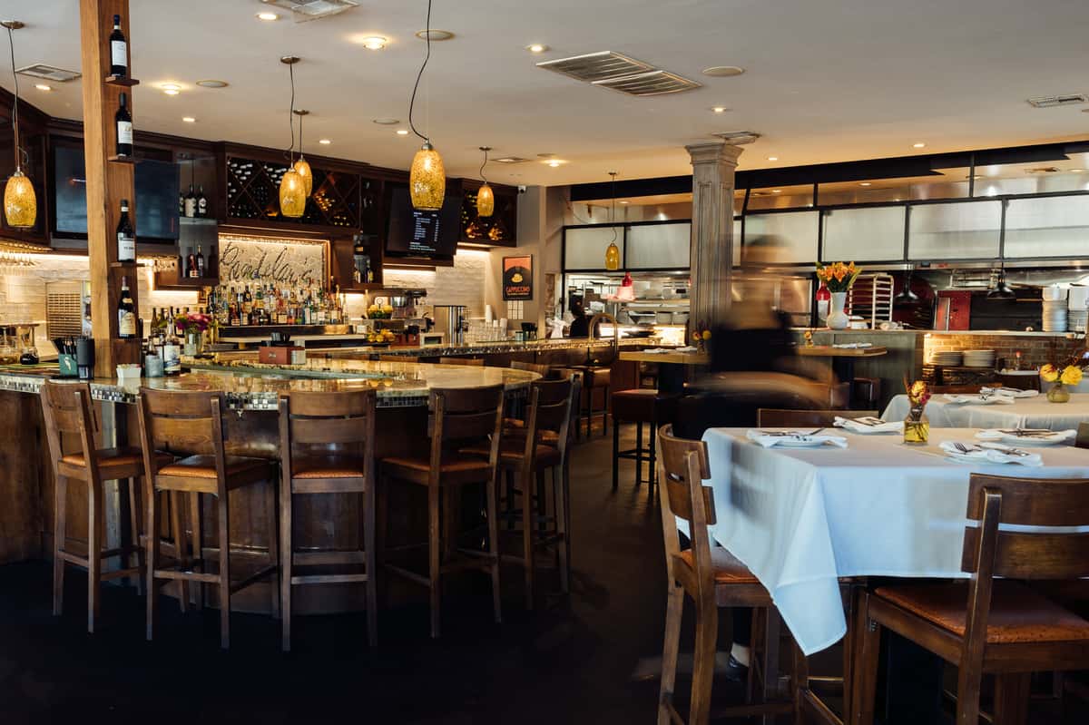 elegant restaurant interior with bar seating, white tablecloth dining, and warm ambient lighting