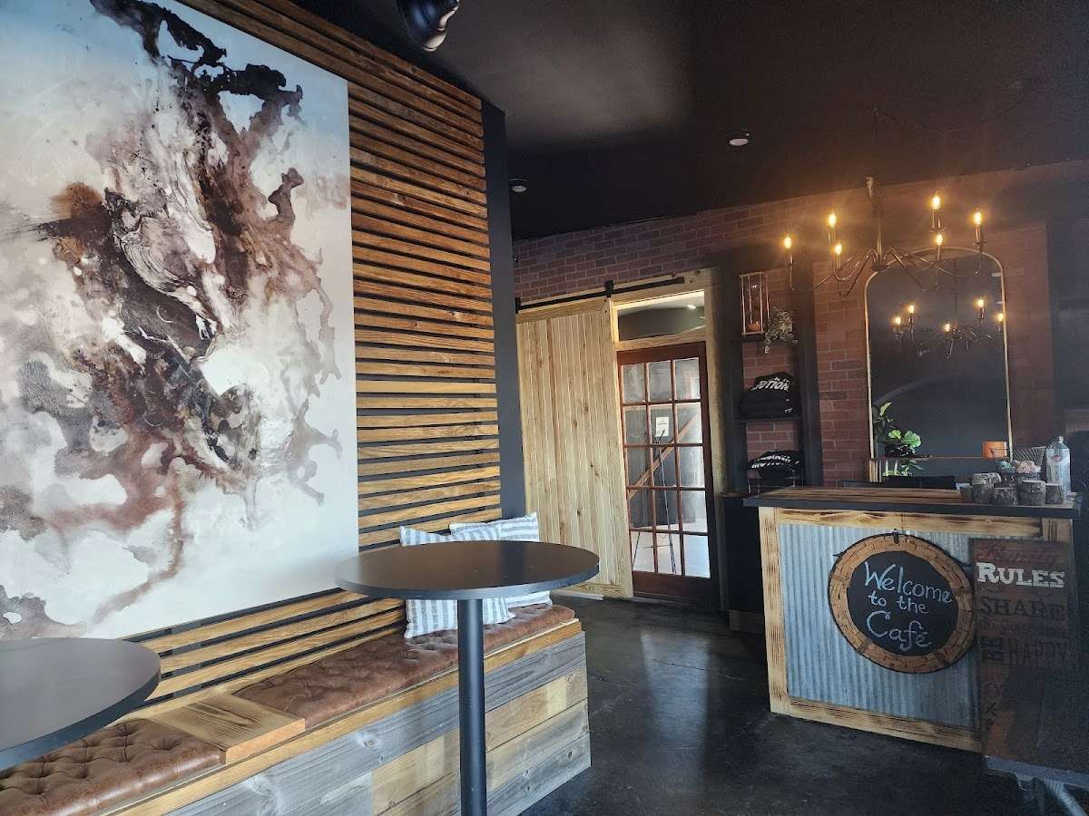 Cozy café interior with rustic wooden accents, a tufted bench, abstract wall art, and a warm chandelier above the counter.