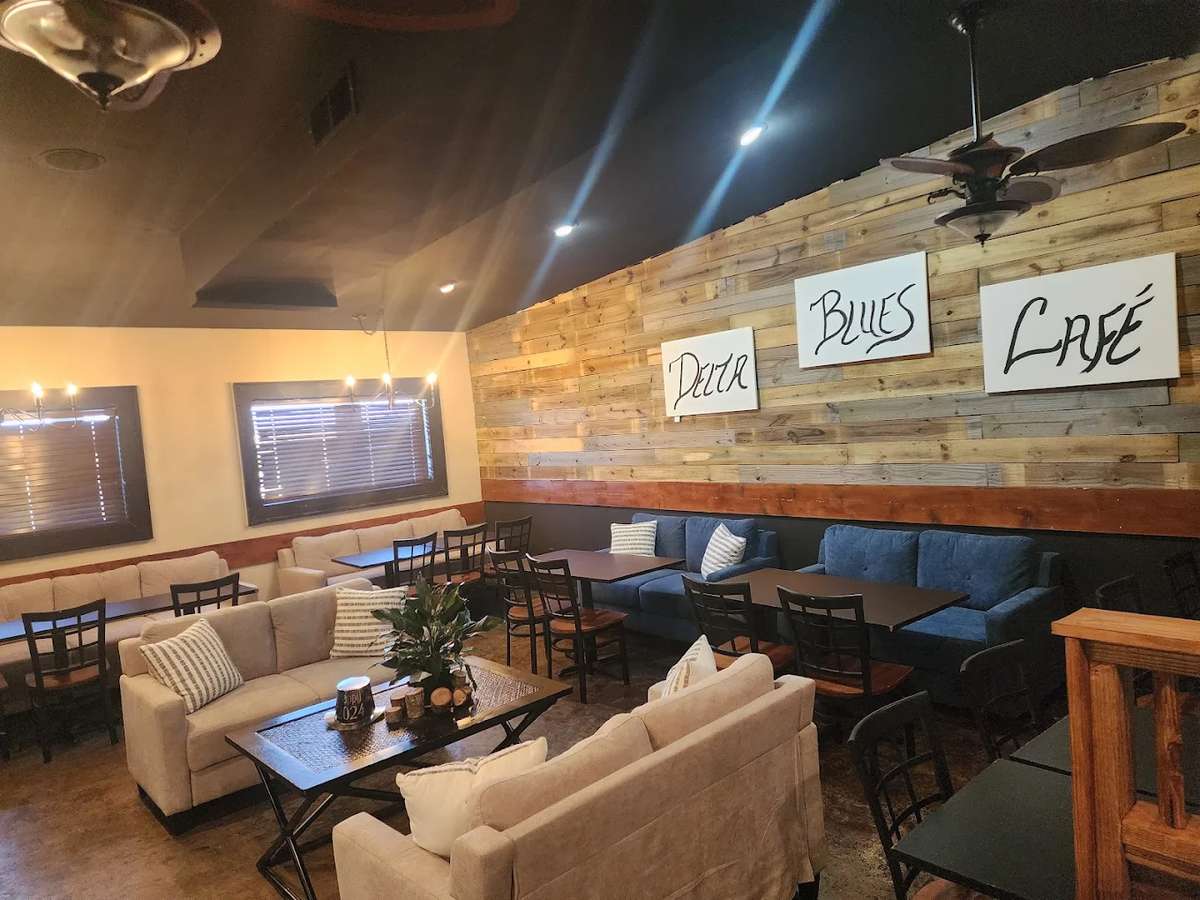Cozy café interior with cushioned seating, wooden accents, and a sign on the wall reading "Delta Blues Café."