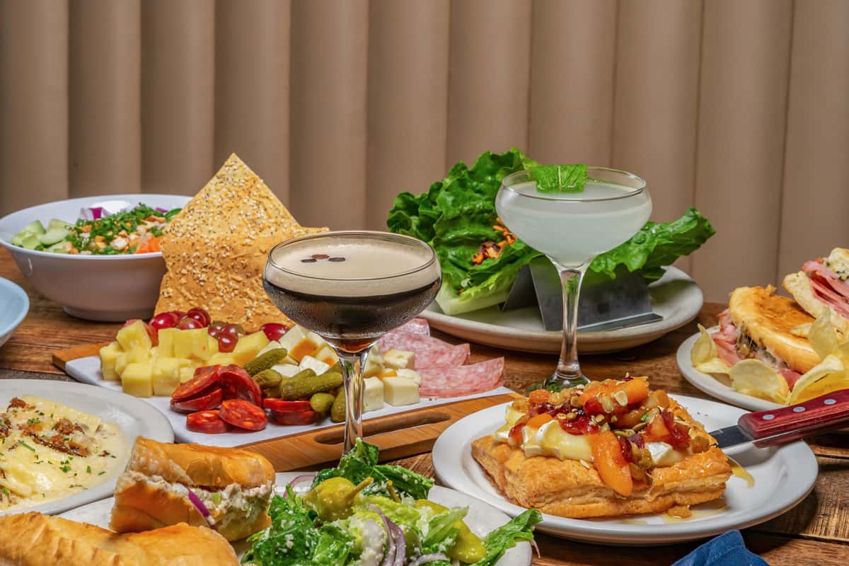 Vibrant spread of food and cocktails, including an espresso martini, charcuterie board, and savory pastries at The Downing Bottles and Bites.