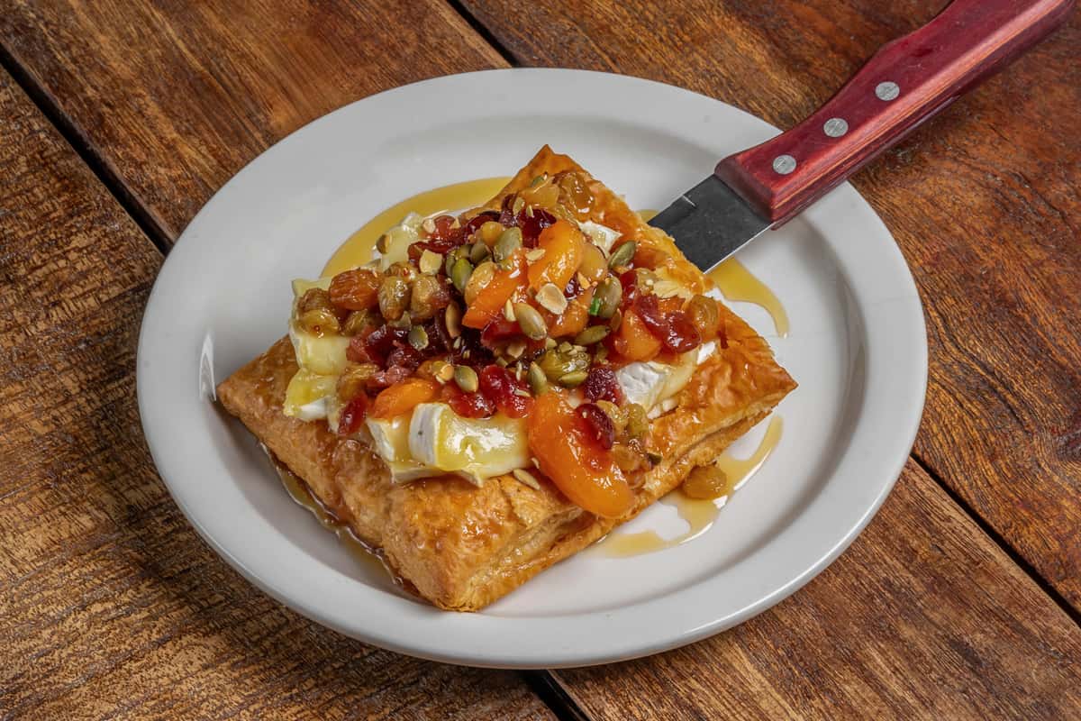 Golden baked Brie puff pastry tart with apricot and fruit preserves, drizzled with honey at The Downing Bottles and Bites.