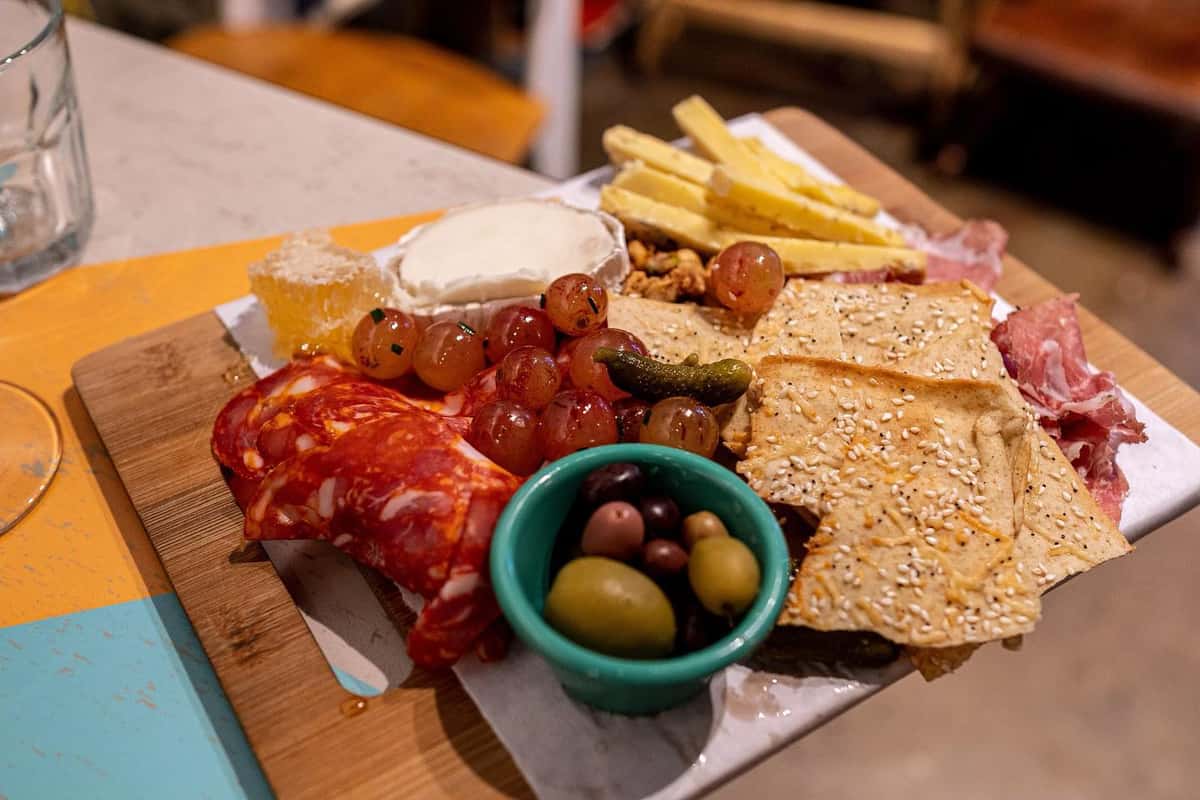 Appetizing charcuterie board with cured meats, brie cheese, grapes, and crackers, served at The Downing Bottles and Bites.