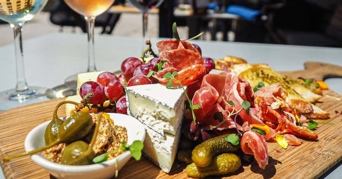 Charcuterie board with cured meats, artisan cheese, olives, grapes, figs, and crackers, perfect for sharing with wine or cocktails.