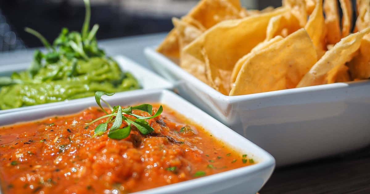 Creamy queso dip topped with fresh herbs, served with crispy tortilla chips as a flavorful appetizer at the restaurant.