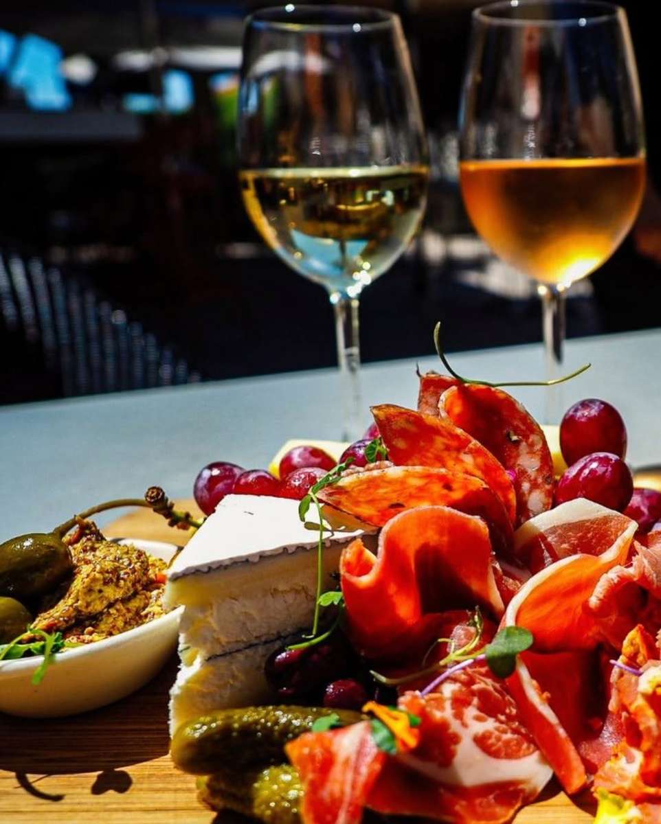 Charcuterie board with artisan cheeses, cured meats, fresh fruit, and wine, perfect for sharing at the restaurant.