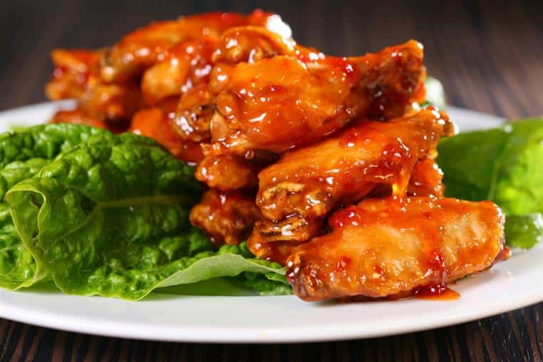 chicken wings on a plate with lettuce underneath