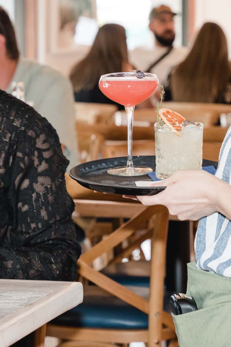 server bringing cocktails on tray to guests