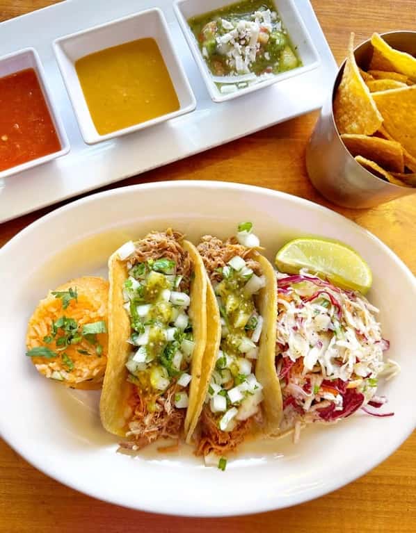 Mesero shredded chicken tacos with rice, slaw, lime, and salsas served with chips for a fresh Tex-Mex meal.