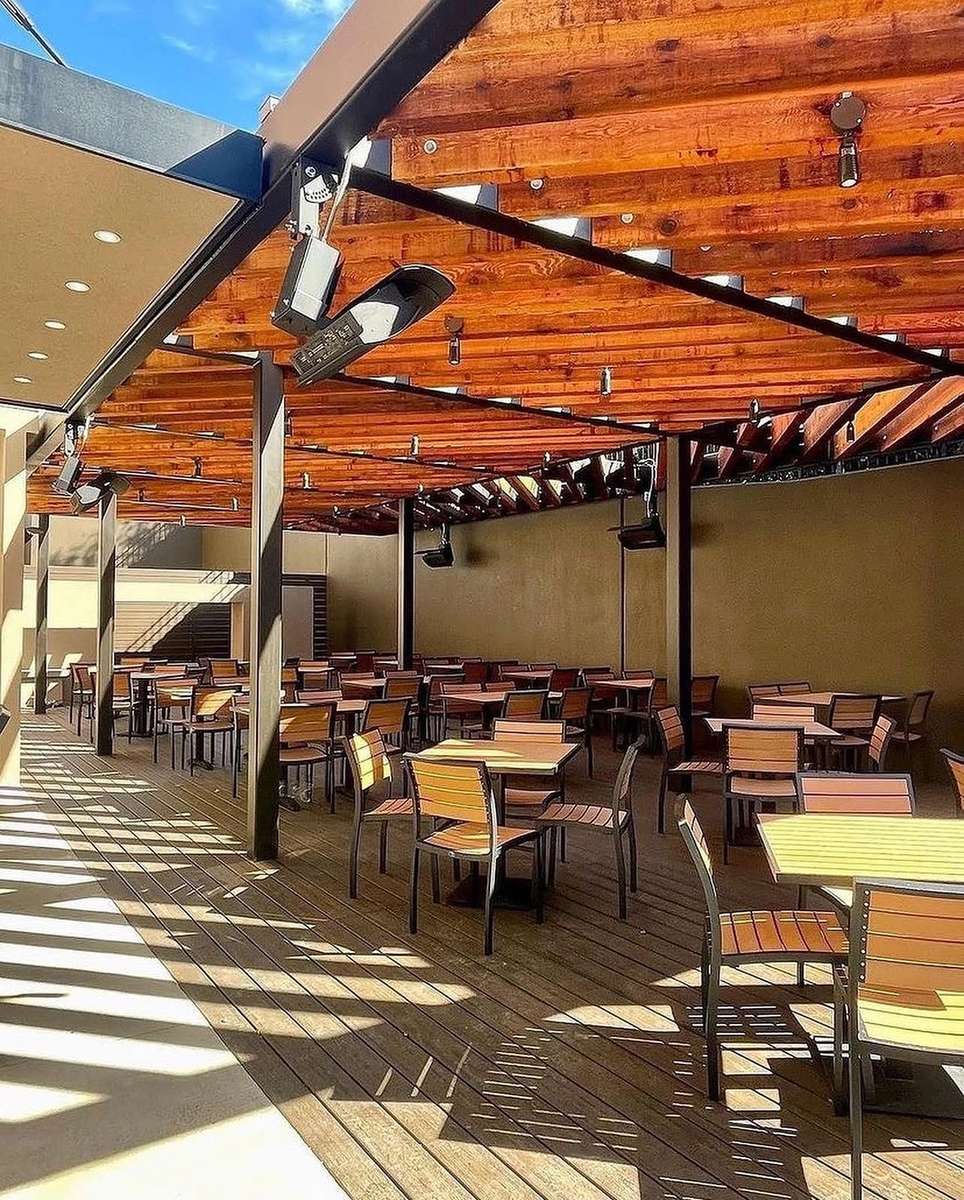 Mesero patio with warm wood beams, outdoor tables, and open-air seating.
