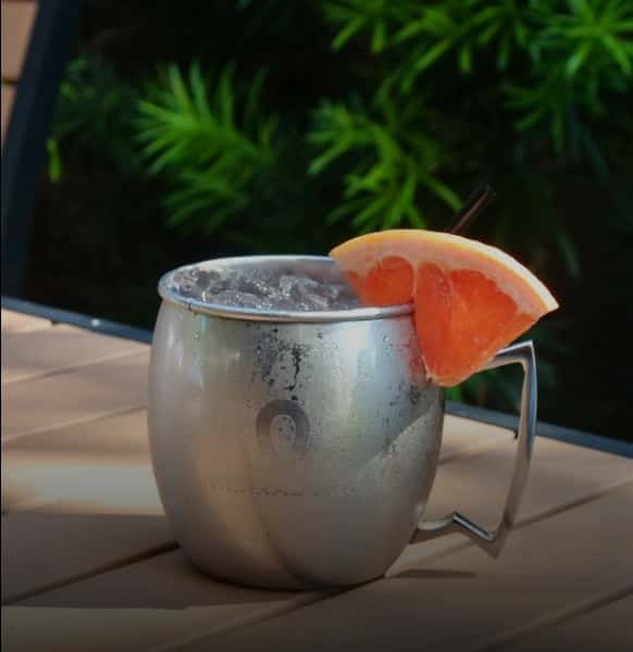 Mesero tequila cocktail served in a chilled metal mug with fresh grapefruit slices on a sunny outdoor patio.