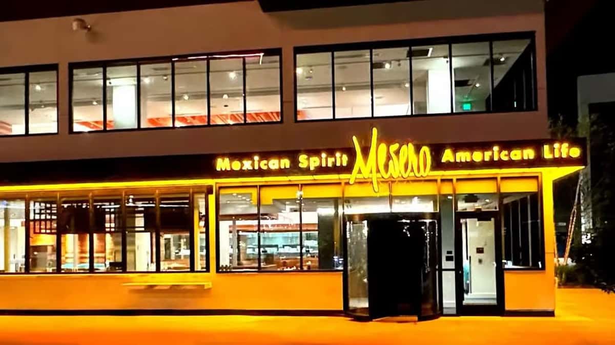 Exterior view of Mesero restaurant at night with bright yellow signage reading 'Mexican Spirit, American Life.'