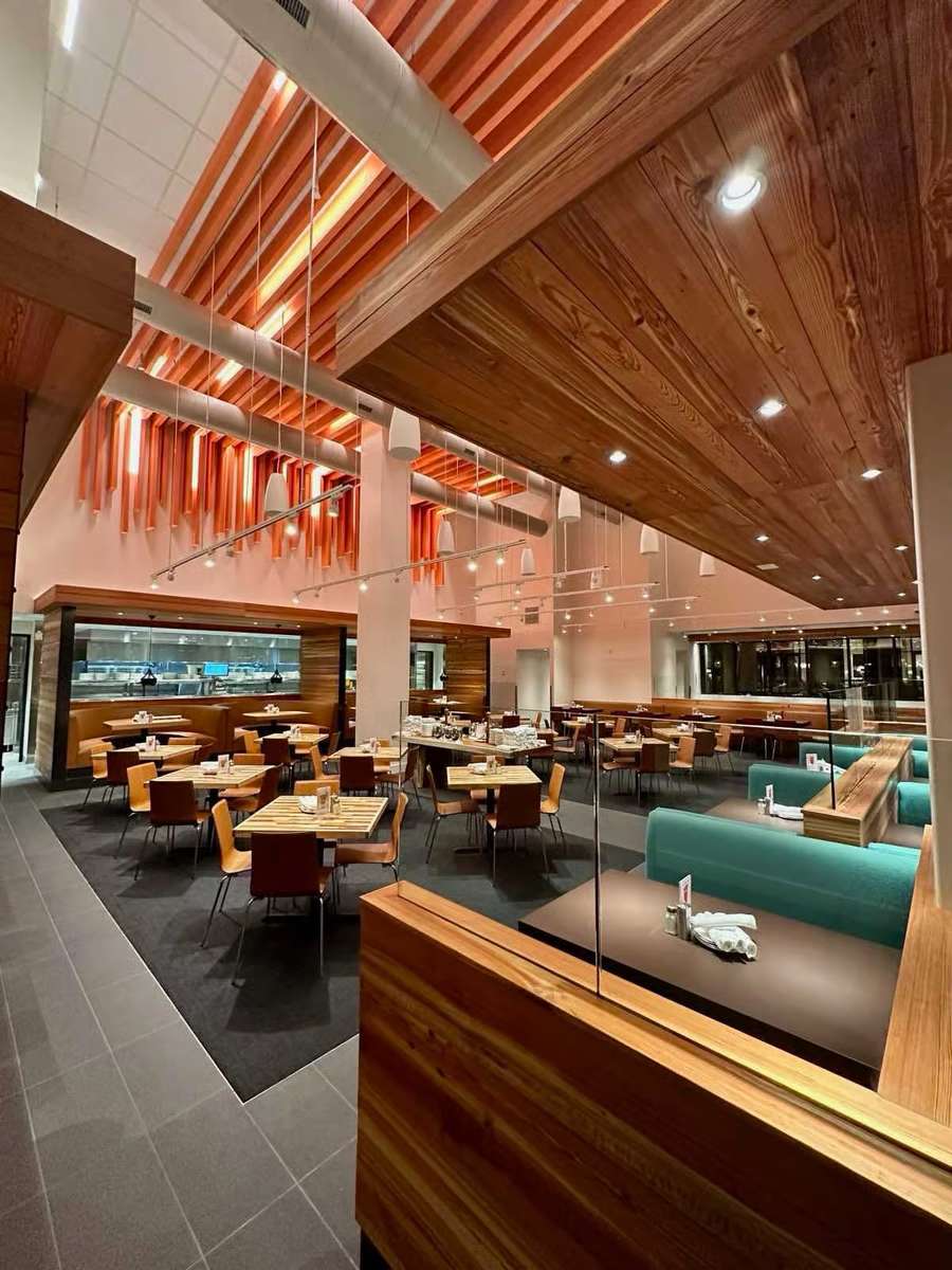 Interior of Mesero restaurant featuring wooden accents, teal booths, and warm orange ceiling beams.