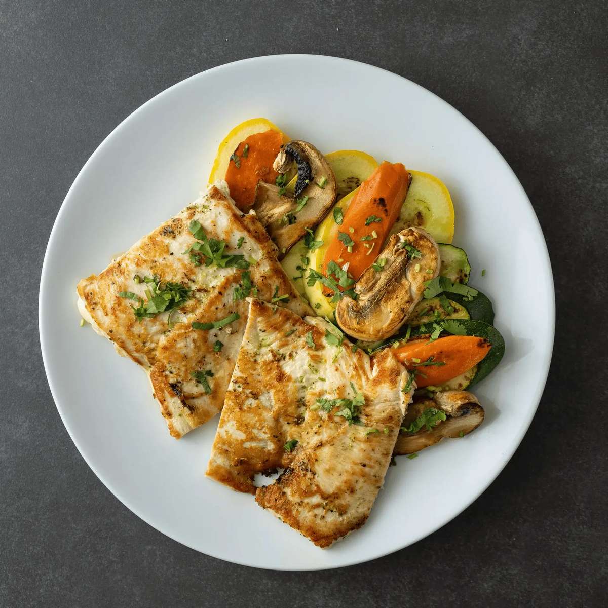 Mesero's grilled chicken served with sautéed vegetables including mushrooms, carrots, zucchini, and yellow squash.