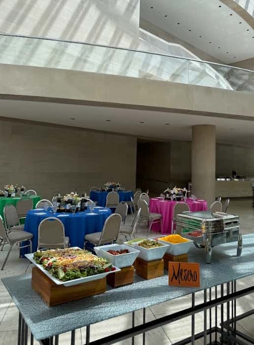Mesero buffet display with fresh salads and chafing dish at elegant indoor event venue.