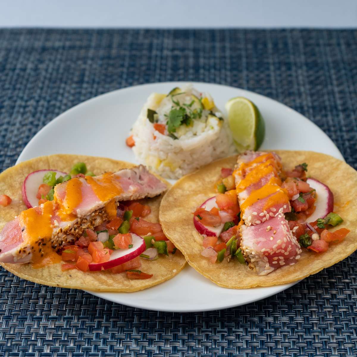 Seared tuna tacos topped with pico de gallo and spicy sauce, served with rice at Mesero.