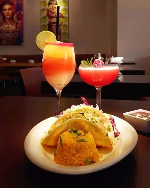 Taco plate with Mexican rice and two vibrant cocktails served at Mesero's modern dining space.