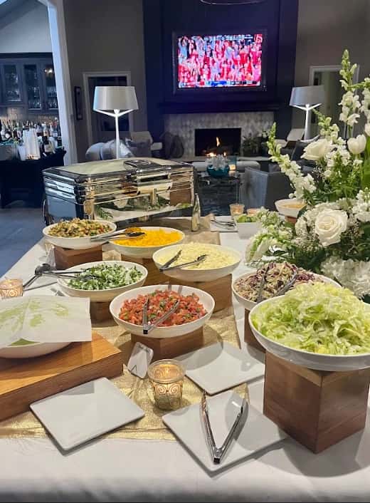 Elegant Mesero buffet setup with fresh salads, salsa, and chafing dishes in a cozy lounge setting.