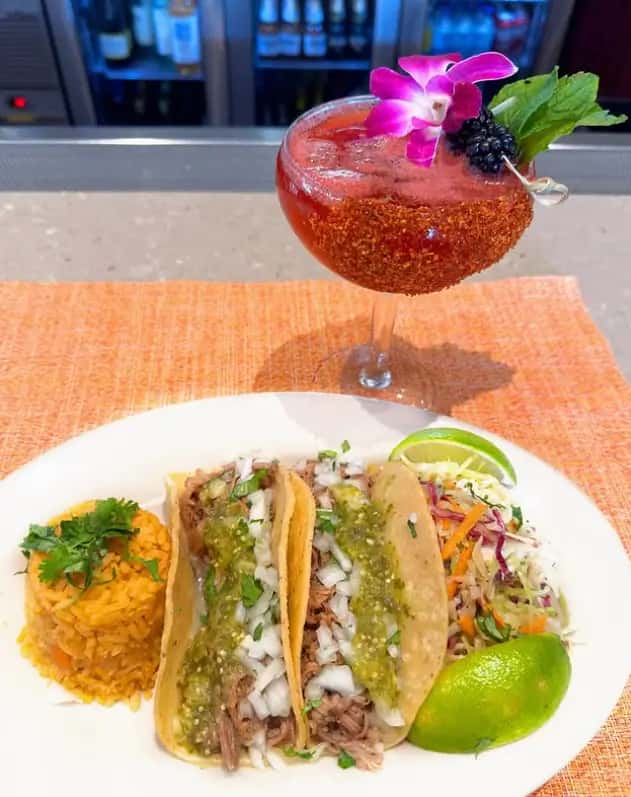 Mesero tender brisket tacos topped with onions and cilantro, served with rice and fresh sides.