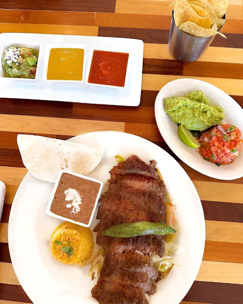 Mesero fajita plate with chips, salsa, queso, guacamole, rice, beans, and tortillas.