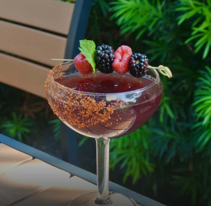 Mesero berry margarita with a spiced rim and fresh berry garnish outdoors.