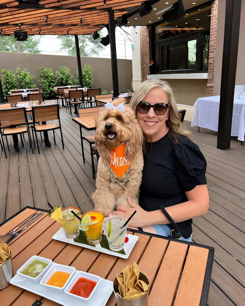 Mesero patio dining with margaritas, chips, salsa, and a guest seated with a dog.