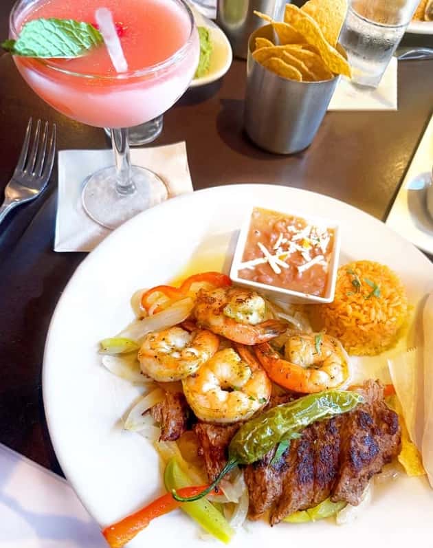 Mesero shrimp and steak fajitas served with rice, beans, chips, and a pink margarita.